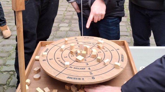 Bomboleo im Spiel – eine Hand zeigt auf einen Klotz auf der Scheibe