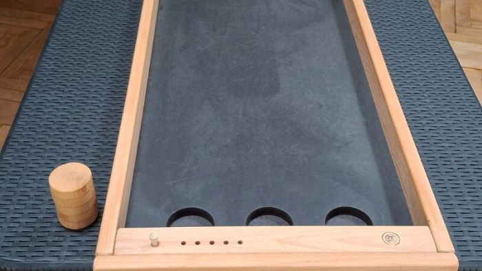 Schibbelmühle auf dem Klapptisch – Golfball in der Mittelmulde, Holzscheiben daneben