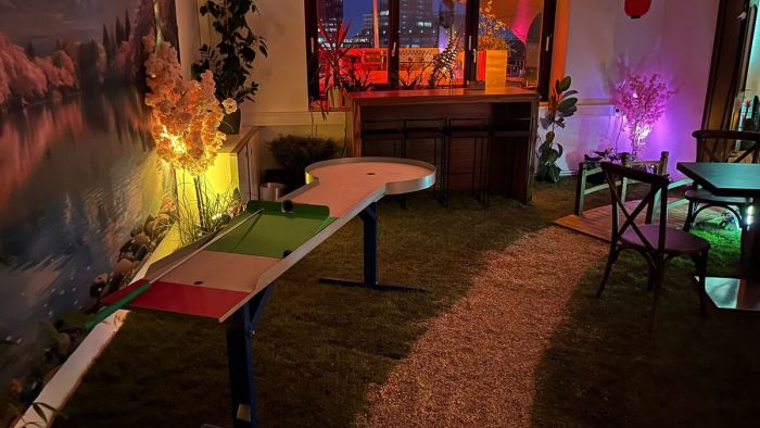 Pit-Pat-Bahn bei einem Abendevent indoor, farbig ausgeleuchtete Eventflaeche mit Bar