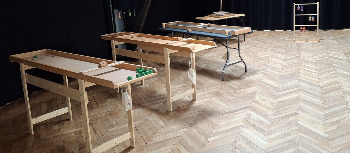 Shuffleboard, Japanisches Billard, Tisch-Curling und Leitergolf in einer Halle aufgebaut
